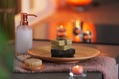 Bottle of shampoo and soap bars on table against blurred background