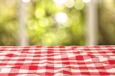 Image of Table with red checkered cloth indoors. Space for design