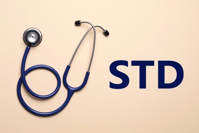Text STD and stethoscope on beige background, top view