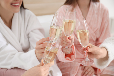 Beautiful young ladies clinking glasses of champagne at pamper party, closeup. Women's Day