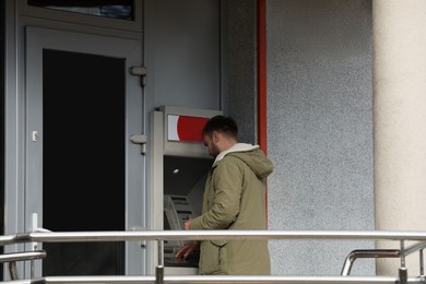 Man using cash machine for money withdrawal outdoors