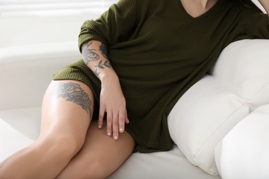 Beautiful woman with tattoos on body resting in living room, closeup