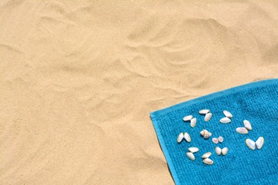 Photo of Towel and seashells on sand, top view with space for text. Beach accessory