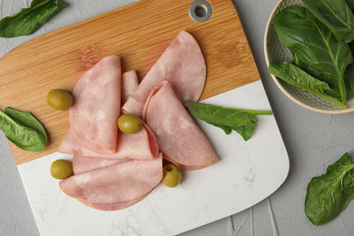 Ham with olives and spinach on light grey table, flat lay