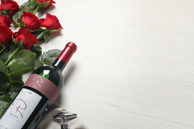 Photo of Bottle of red wine and beautiful roses on white wooden table. Space for text
