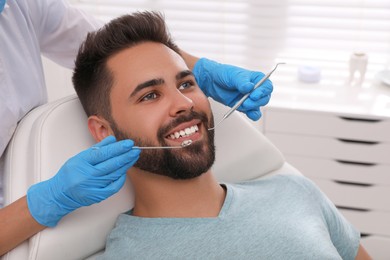 Dentist examining young man's teeth in modern clinic