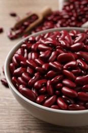 Raw red kidney beans in bowl on wooden table, closeup