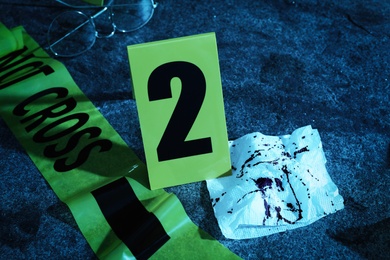 Bloody napkin, tape and crime scene marker on stone table at night