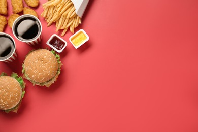 Flat lay composition with delicious fast food menu on red background. Space for text