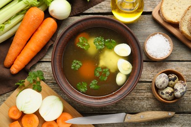 Photo of Delicious chicken bouillon and ingredients on wooden table, flat lay