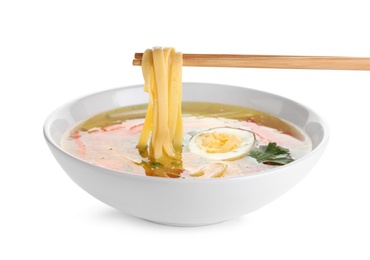 Photo of Chopsticks with noodles over bowl of tasty ramen on white background