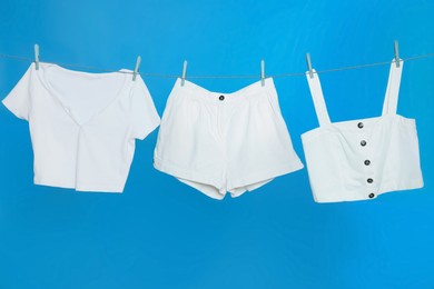 Different clothes drying on laundry line against light blue background
