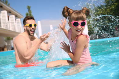 Father and daughter having fun in swimming pool. Family vacation