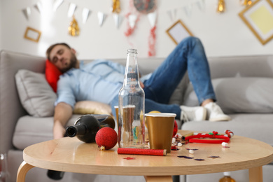 Drunk man sleeping in room after New Year party, focus on messy table