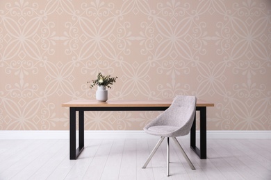 Table and chair near patterned wallpapers. Interior design