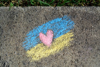 National flag of Ukraine with heart drawn by color chalk on asphalt, top view