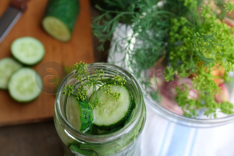 Glass jar with cucumber slices, dill and brine on table, closeup. Pickling recipe