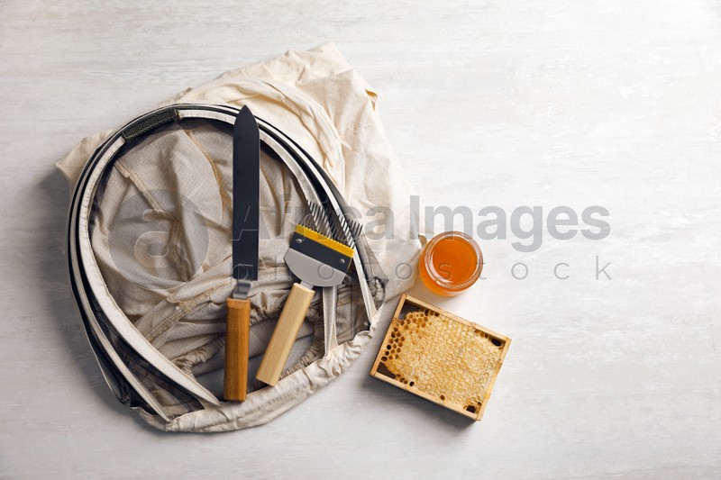 Photo of Different beekeeping tools and jar of honey on white table, flat lay. Space for text