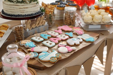 Baby shower party. Delicious cookies on wooden table indoors