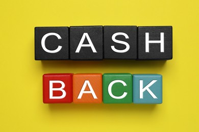 Word Cashback made with cubes on yellow background, flat lay