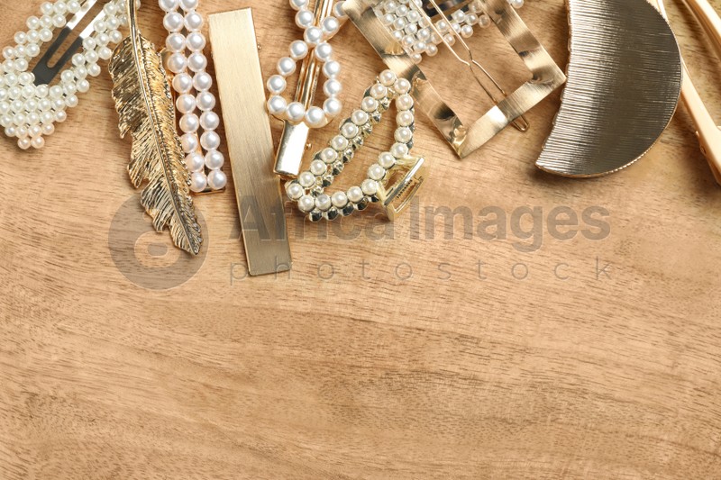 Stylish hair clips on wooden table, flat lay. Space for text