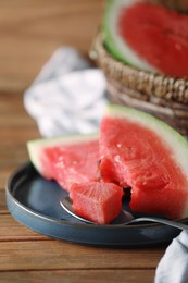 Fresh juicy watermelon and spoon on wooden table, closeup