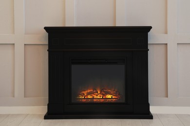 Modern electric fireplace near light wall indoors