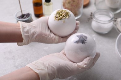 Woman in gloves with self made bath bombs at grey table, closeup