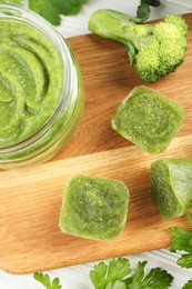 Photo of Frozen broccoli puree cubes and ingredient on cutting board, flat lay