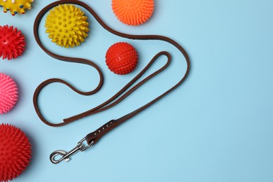 Photo of Flat lay composition with dog leash and toys on light blue background, space for text