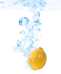 Lemon falling down into clear water against white background