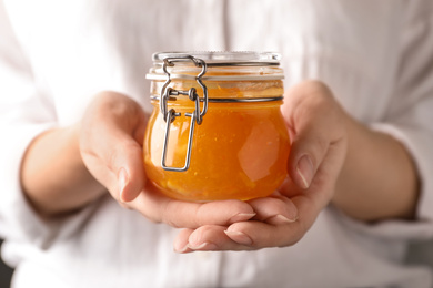 Woman with jar of orange jam, closeup