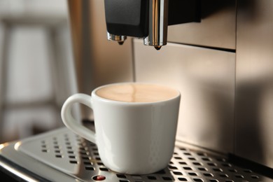 Espresso machine with cup of fresh coffee on drip tray against blurred background, closeup
