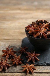 Aromatic anise stars with bowl on wooden table