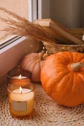 Scented candles and pumpkins on window sill indoors