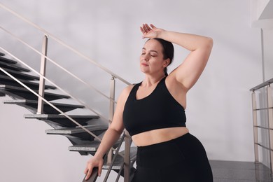 Tired overweight woman on stairs indoors. Space for text