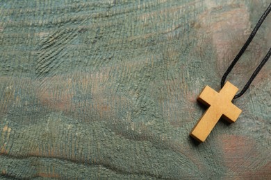Christian cross on wooden table, top view. Space for text