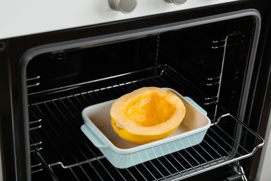 Photo of Baking dish with half of fresh spaghetti squash in oven