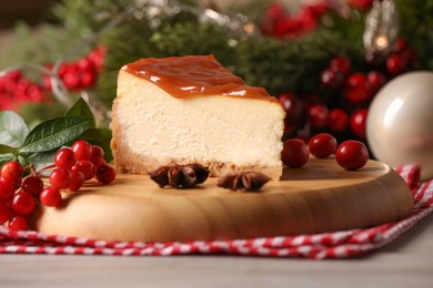 Photo of Tasty caramel cheesecake and Christmas decorations on wooden table