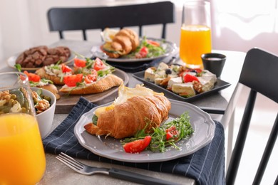 Tasty croissant sandwich and many different dishes served on buffet table for brunch