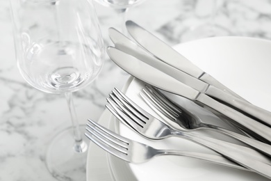 Plates with knives forks on white marble table, closeup