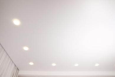 White stretch ceiling with spot lights in room, low angle view