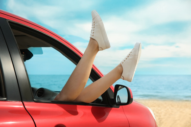 Woman showing legs from car, closeup. Summer vacation trip