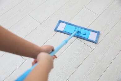 Woman cleaning parquet floor with mop, closeup