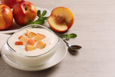 Delicious yogurt with fresh peach on light wooden table, space for text