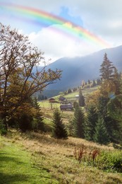 Beautiful rainbow in blue sky over village in mountain on sunny day