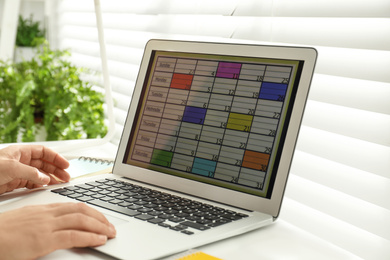Photo of Man using calendar app on laptop in office, closeup