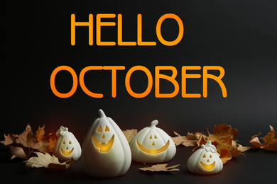 Hello October card. Jack-o-Lantern candle holders as Halloween decor and autumn dry leaves on black table