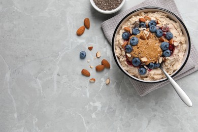Tasty oatmeal porridge with toppings served on grey table, flat lay. Space for text