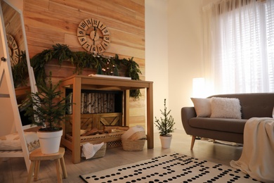Cozy room interior with console table and conifer garland near wooden wall